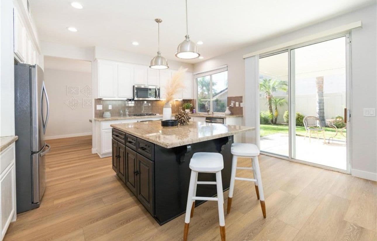 Modern kitchen with island, stainless steel appliances, and bright natural light.