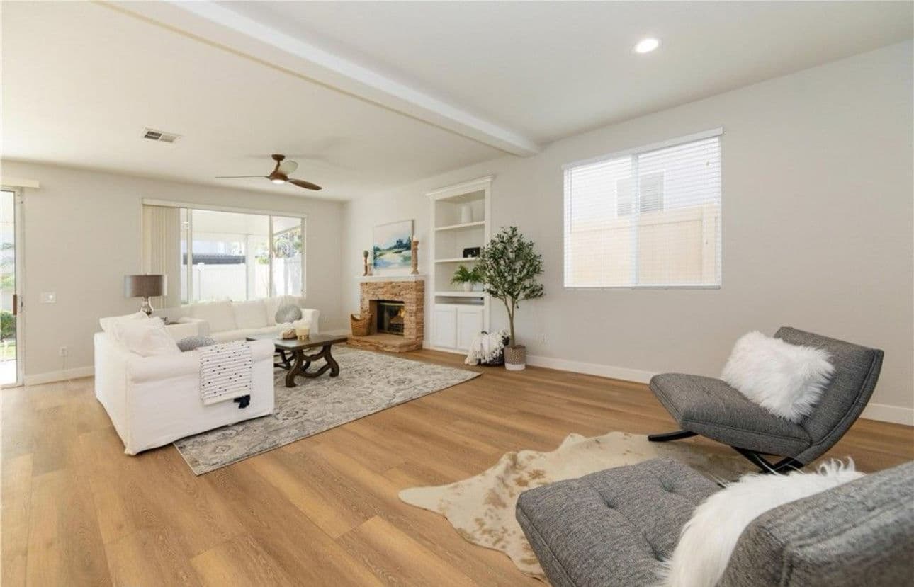 Modern living room with white furniture, wooden floors, and cozy fireplace decor.