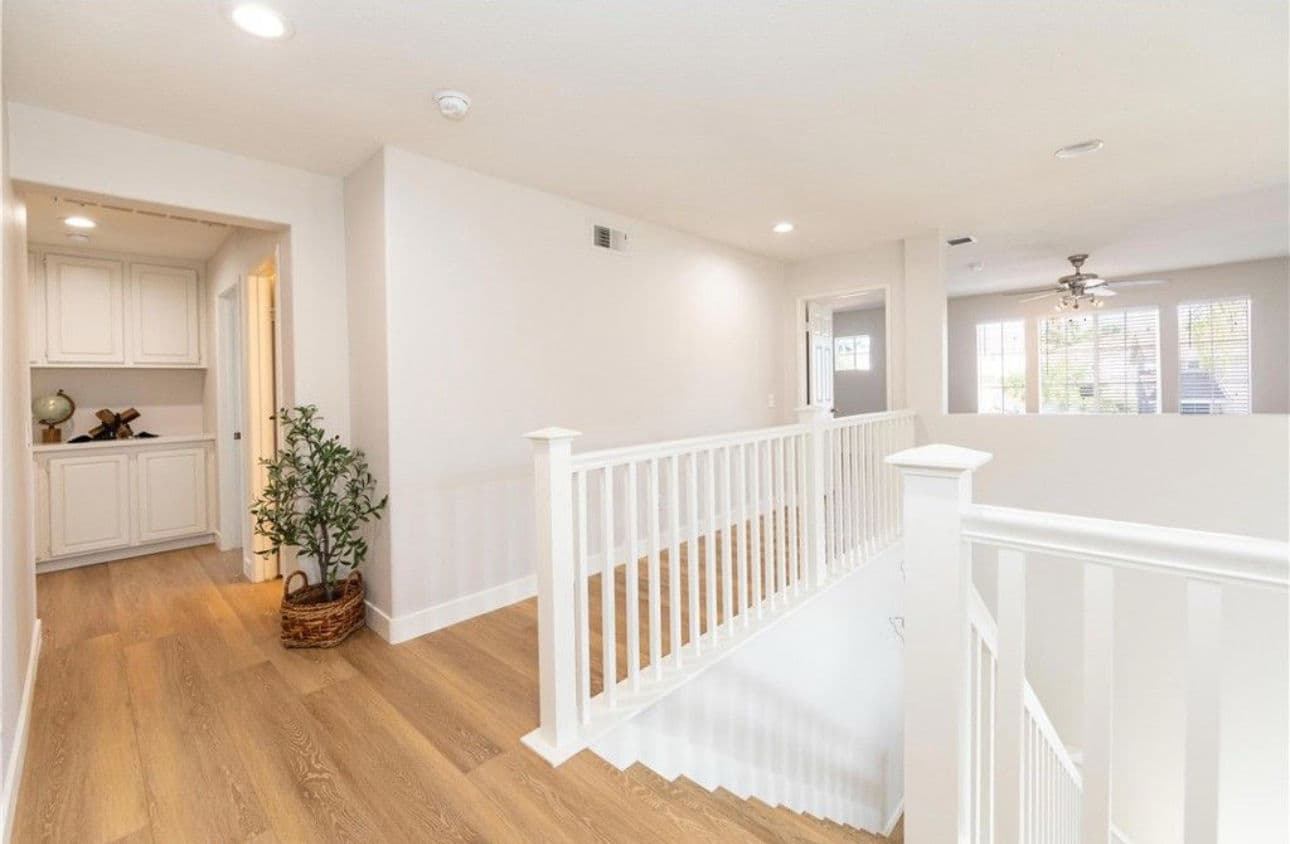 Bright modern staircase in a spacious hallway with wood flooring and natural light.