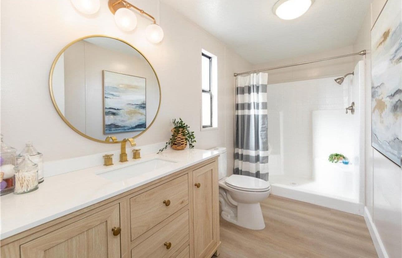 Modern bathroom with wood vanity, round mirror, and shower curtain in neutral tones.