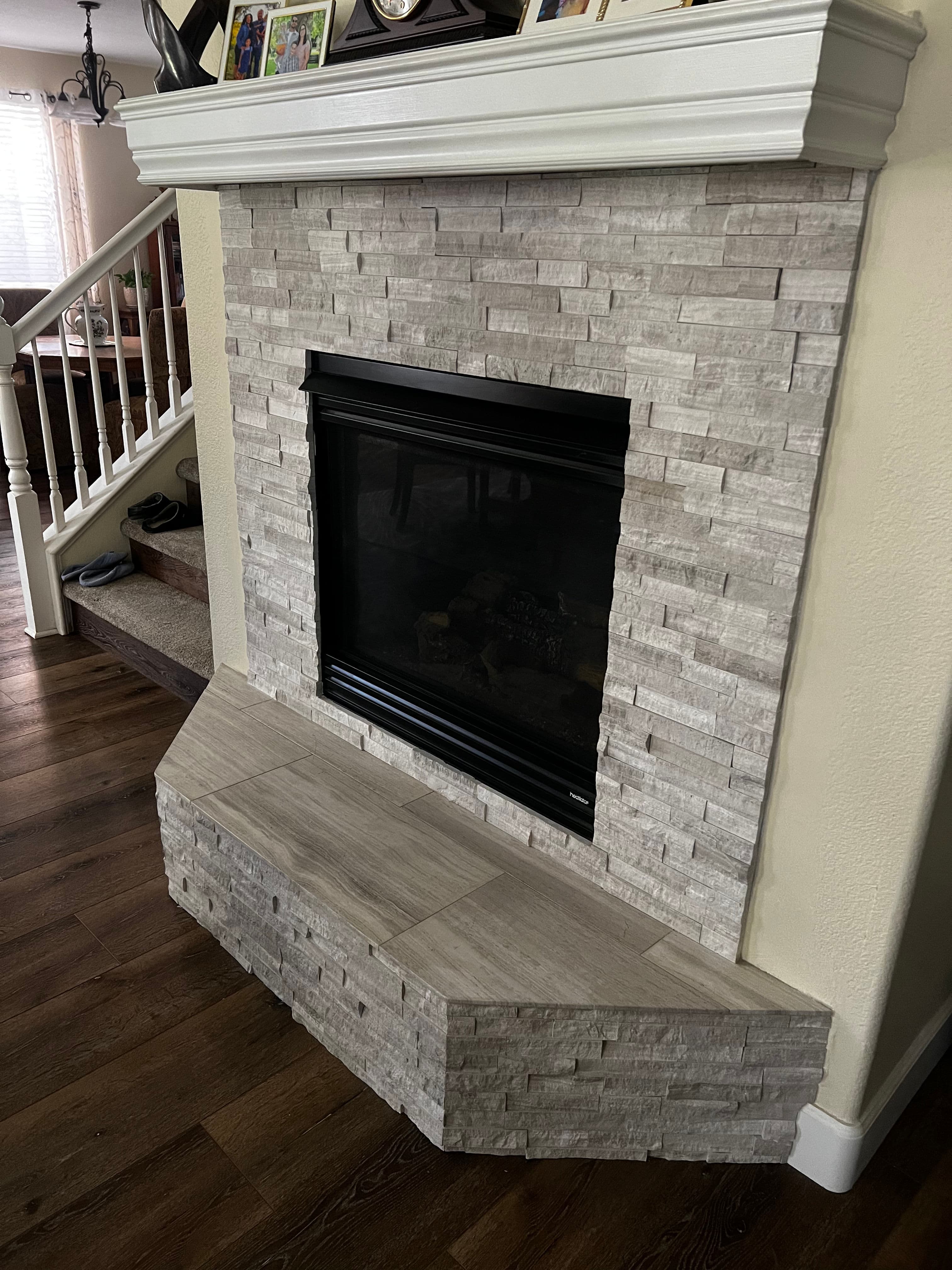 Modern stone fireplace with a wooden mantel and sleek, curved hearth in a cozy living room.